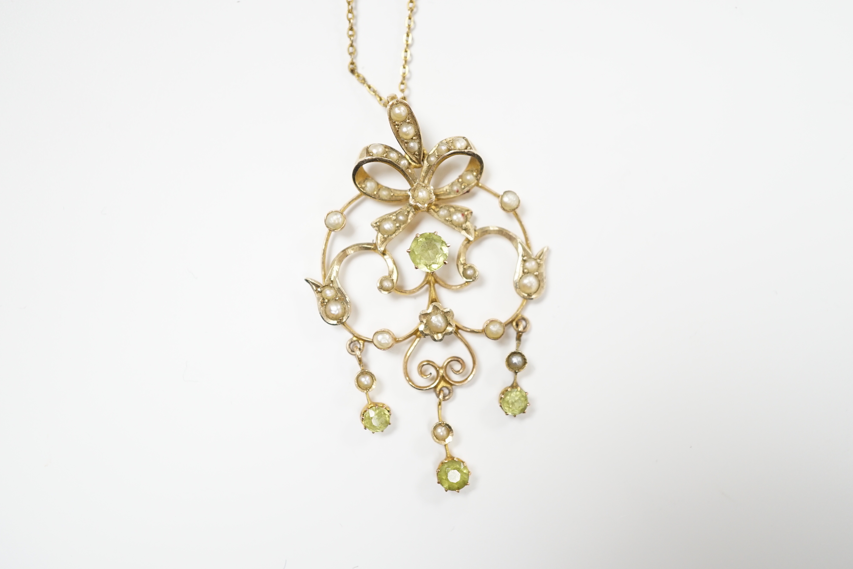 An Edwardian 9ct, peridot and seed pearl cluster set drop pendant, 47mm, on a gilt metal chan.